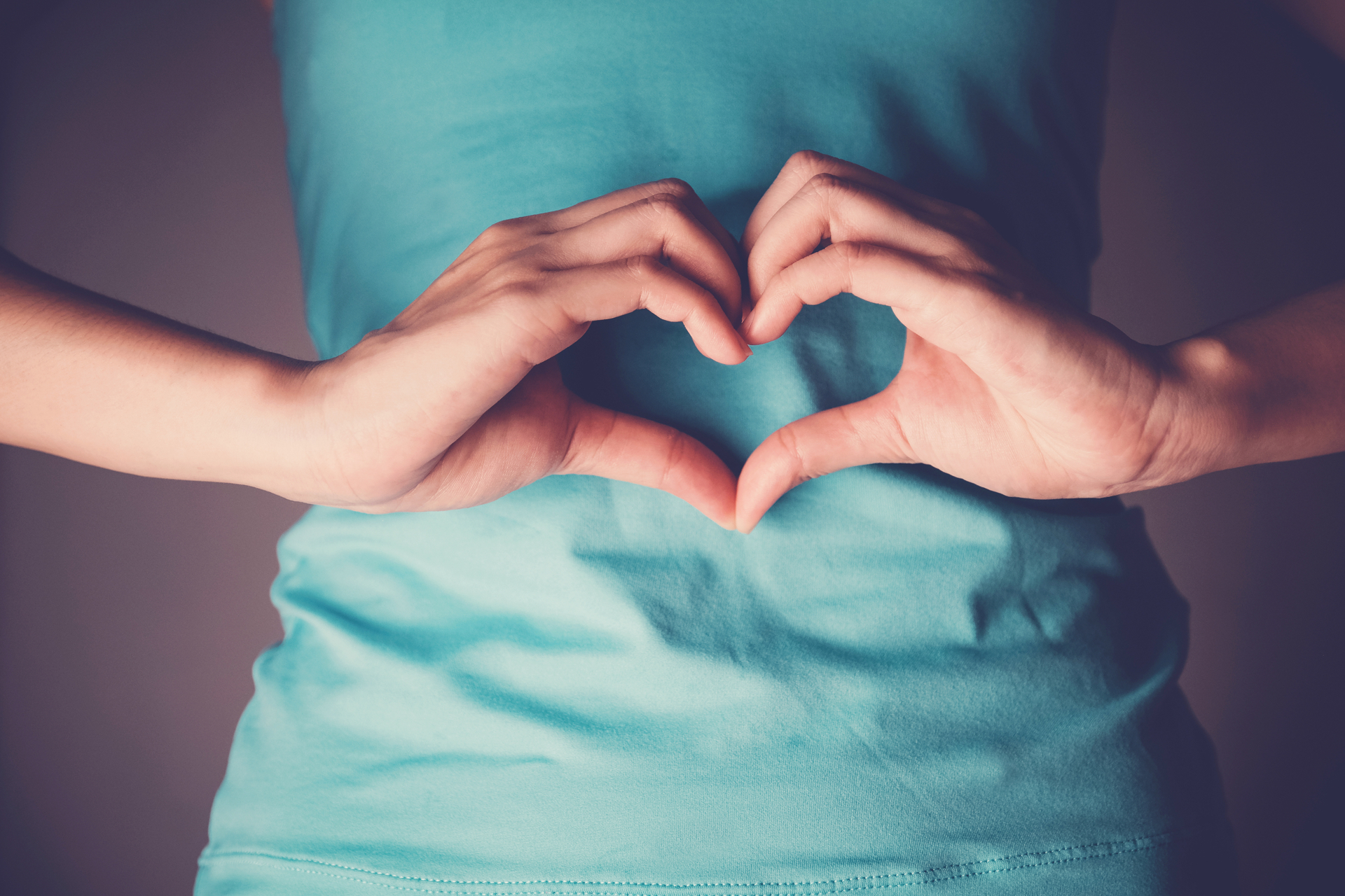 Hands forming a heart shape over the stomach, symbolising listening to your body
